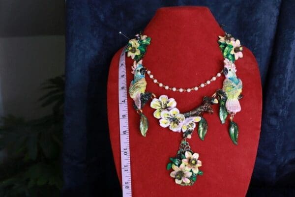 A red mannequin wearing a necklace and earrings.