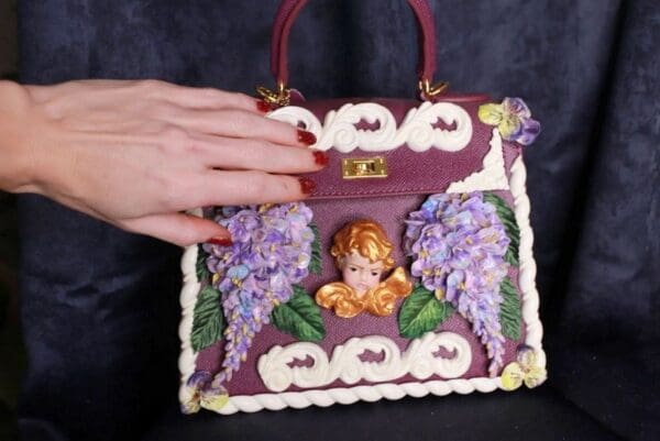 A hand is holding onto a purple purse with flowers.