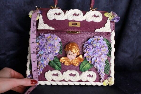 A purple purse with a picture of a baby angel.