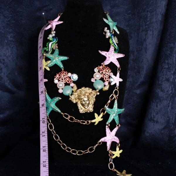 A black mannequin wearing a necklace with stars and flowers.
