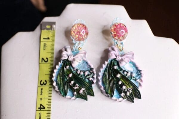 A pair of earrings with flowers and ribbons on them.