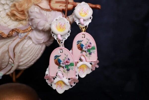 A pair of earrings with pink and white flowers.