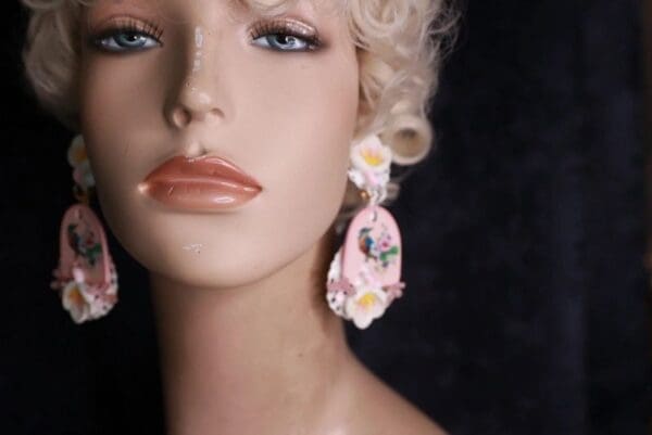 A mannequin wearing pink earrings with flowers.