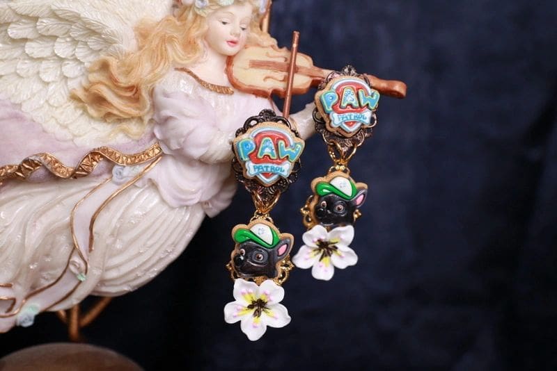 A pair of earrings with flowers and a fairy.
