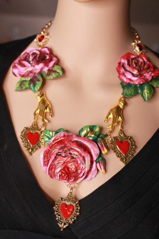A woman wearing a necklace with roses and hearts.