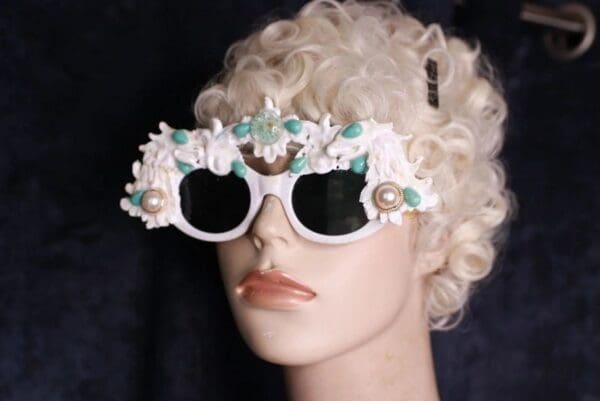 A mannequin wearing white sunglasses with flowers on them.
