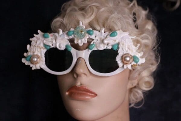 A mannequin wearing white sunglasses with turquoise accents.