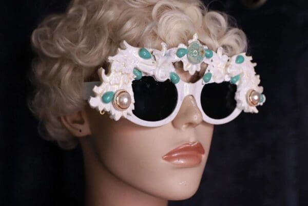 A mannequin wearing white sunglasses with blue stones.