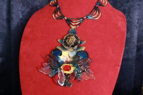 A red background with a necklace and a large pendant.
