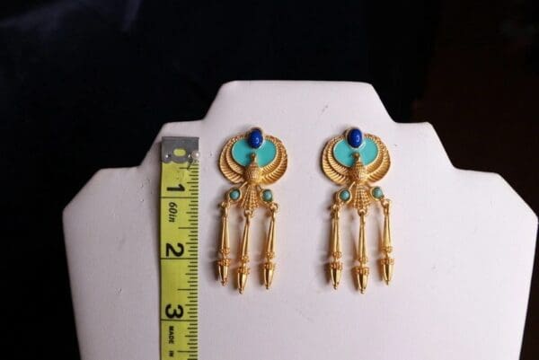 A pair of earrings on display next to a ruler.