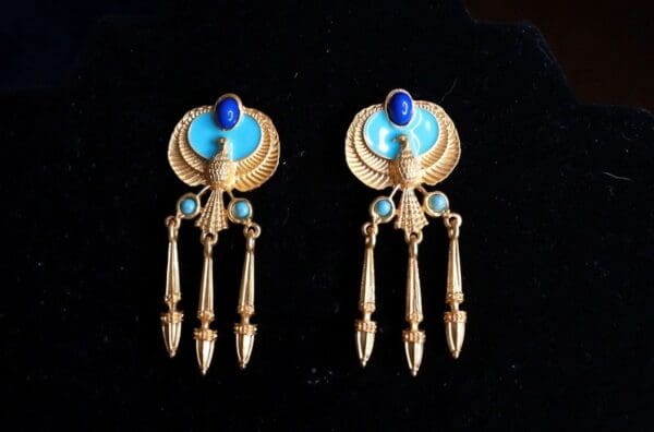A pair of earrings with blue and gold accents.