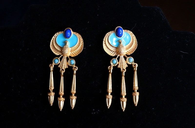 A pair of earrings with blue and gold accents.