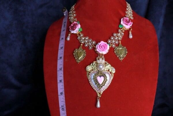 A red mannequin wearing a necklace with pink roses.