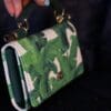 A person holding onto a green and white purse