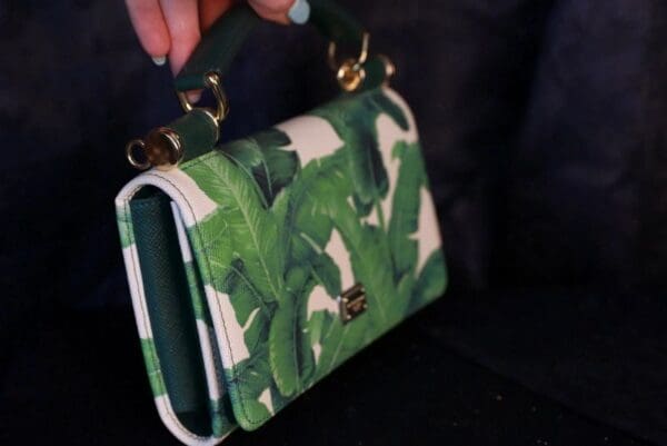 A person holding onto a green and white purse