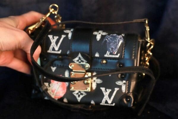 A person holding a purse with a chain strap.