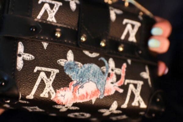 A close up of the bottom of a purse with a cat and mouse on it.