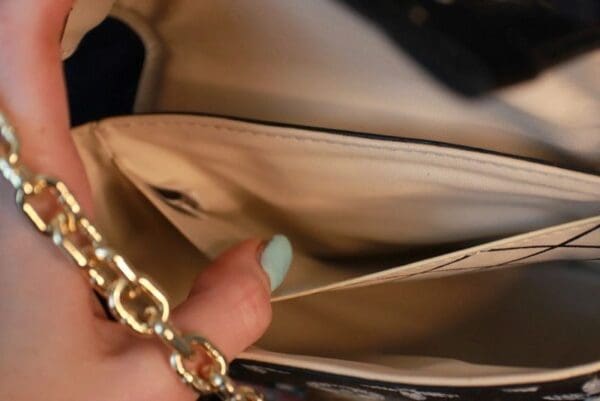 A person holding onto the chain of their purse