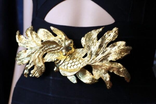 A woman wearing a black dress with gold leaves on it.