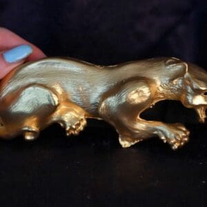 A hand is holding onto a gold statue