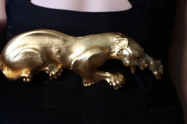 A gold statue of a bear on top of a black table.