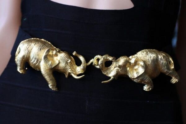 Two gold elephants are touching each other.