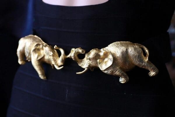 A woman wearing black and gold belt with two elephants.