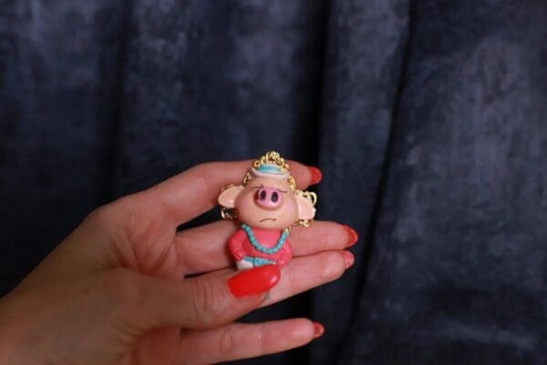 A person holding a small toy pig in their hand.