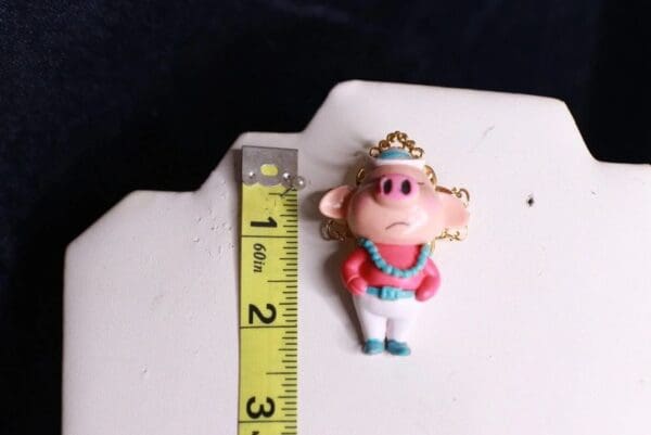 A small toy is shown next to a ruler.
