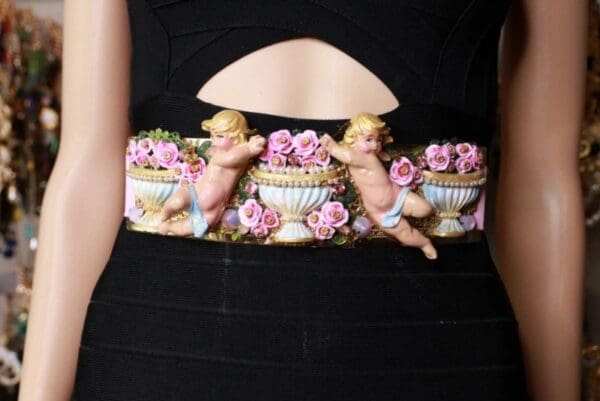 A woman wearing a black dress with pink flowers and two cherubs.