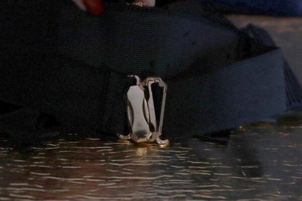 A penguin is standing on the ground in water.