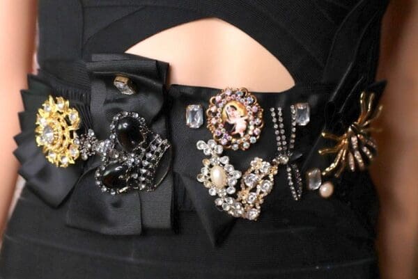 A woman 's black dress with many different jewelry.