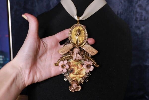 A person holding onto a necklace with a picture of jesus