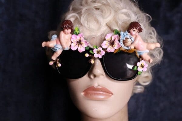 A mannequin wearing sunglasses with cherubs on them.