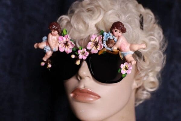 A mannequin wearing sunglasses with cherubs and flowers on them.