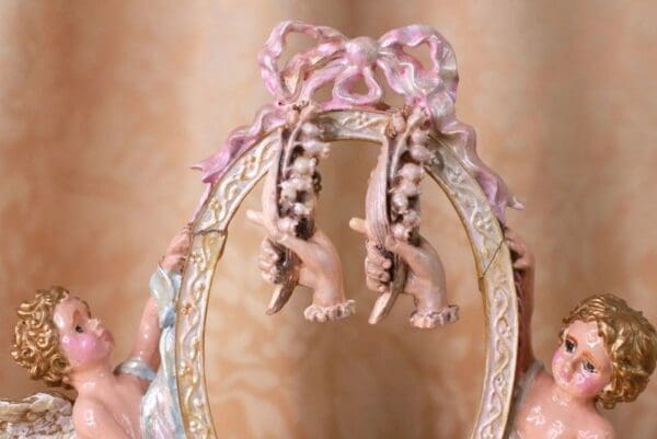 A pair of pink elephants hanging from the side of a decorative frame.
