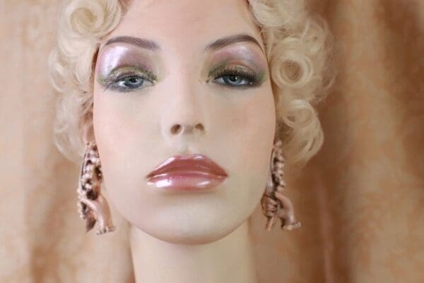 A mannequin with long earrings and pink lipstick.