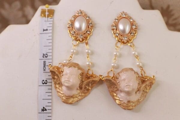 A pair of earrings with gold chain and pearls.