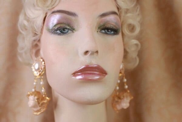 A mannequin with long earrings and pink lipstick.
