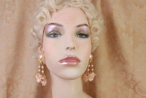 A mannequin with pink pearls and gold earrings.