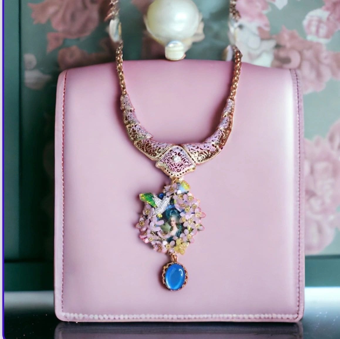A pink purse with a blue and white necklace on it