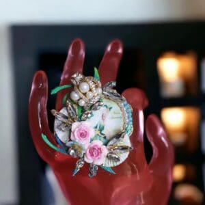 A red hand holding a shell with flowers on it.