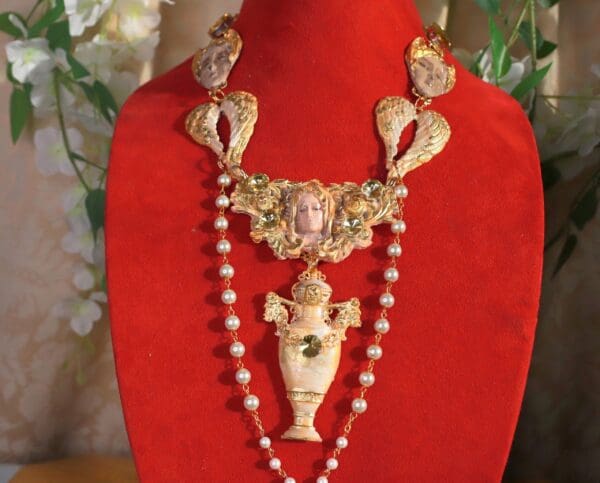 A red velvet display with a necklace and a vase.