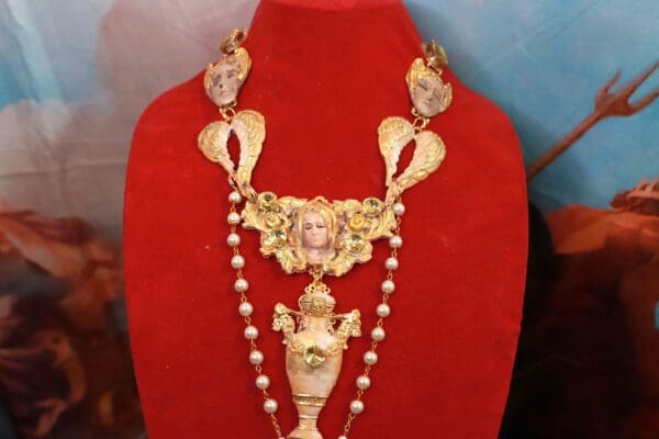 A red velvet display with a necklace and a statue.