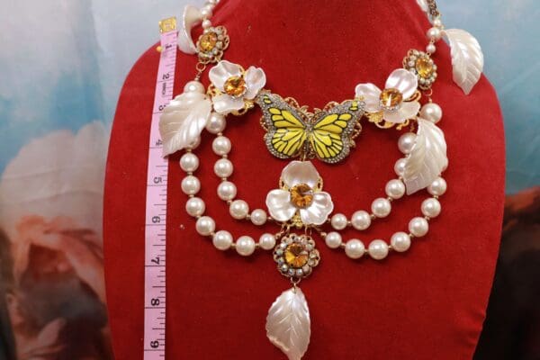 A red velvet display with a butterfly and pearls.