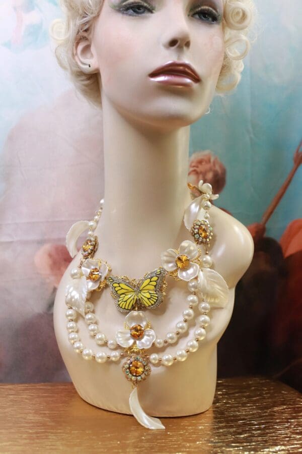A mannequin wearing a necklace with pearls and butterfly.