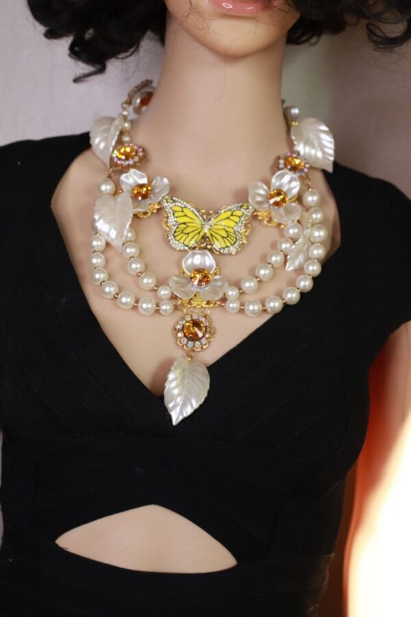 A woman wearing a necklace with pearls and leaves.
