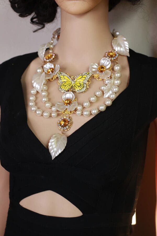 A woman wearing a necklace with pearls and gold leaves.