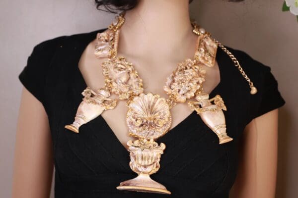 A woman wearing a necklace with gold flowers and a vase.
