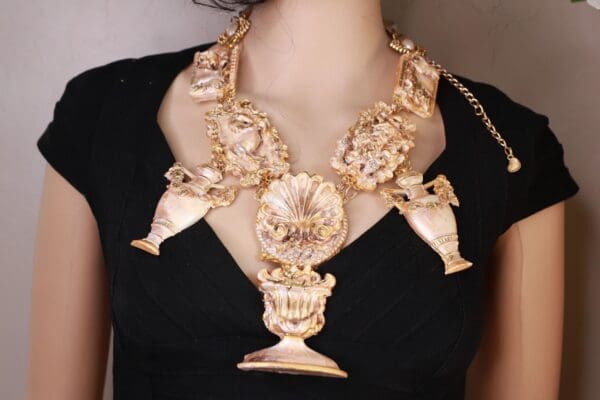 A woman wearing a necklace with gold flowers and a vase.